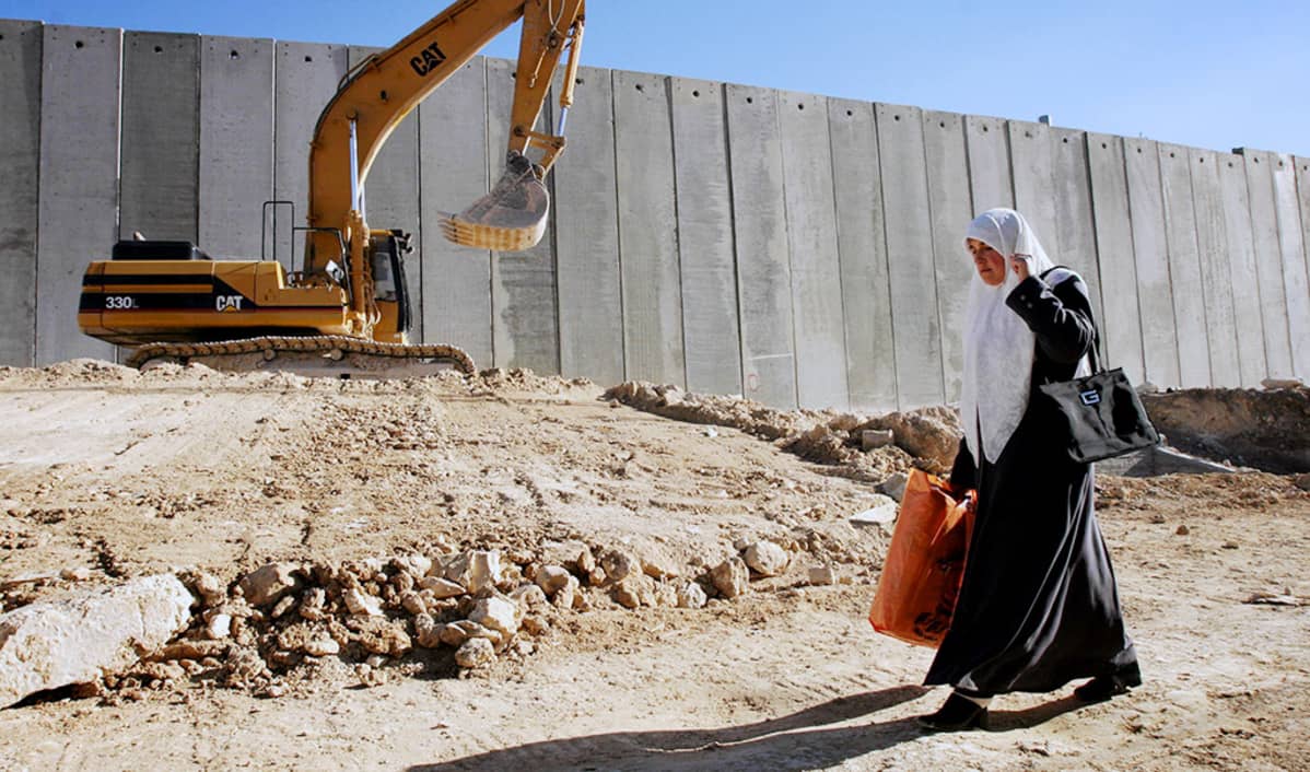 Palestiinalainen nainen kävelee israelilaisten rakentaman muurin vierustalla Itä-Jerusalemissa.
