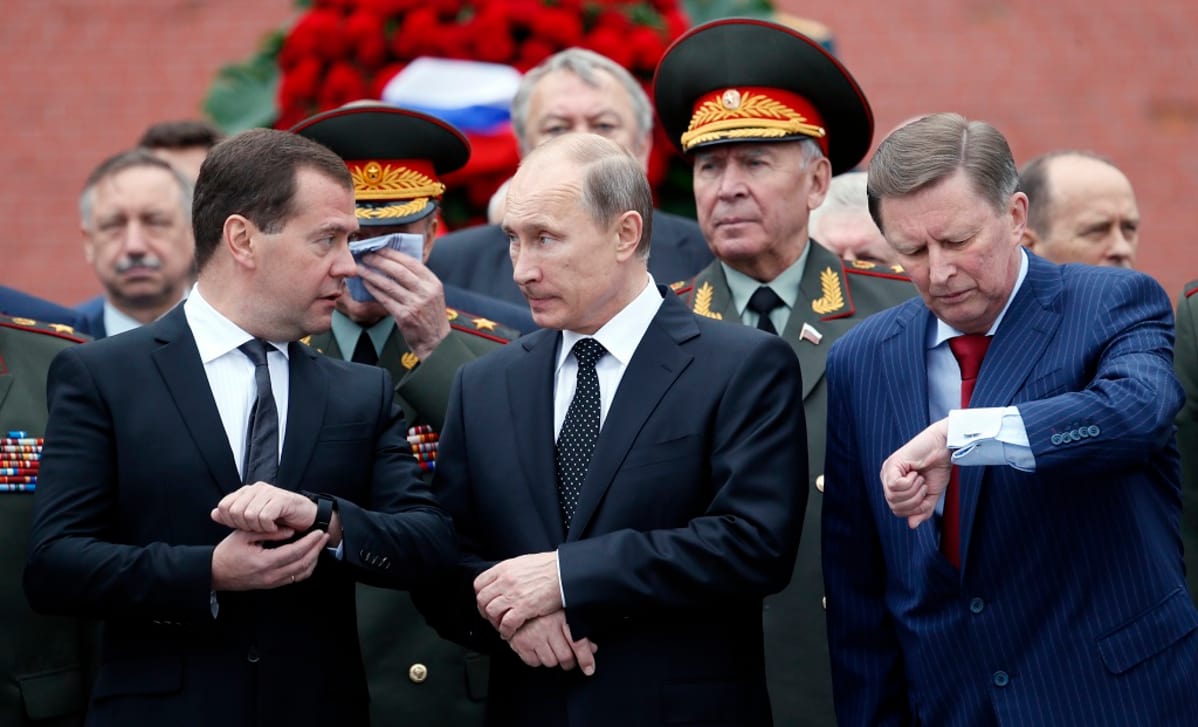 Venäjän pääministeri Dimitri Medvedev (vas.), presidentti Vladimir Putin ja hallintopäällikkö Sergei Ivanov (oik.) vierekkäin tutkimassa kellojaan. Taustalla sotilashenkilöitä.