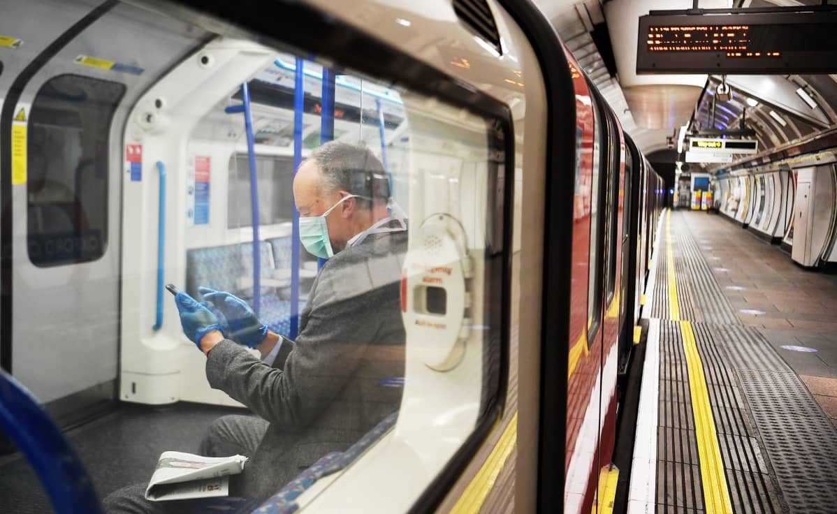 KAsvomaskiin mukeutunut matkustaja autiossa Lontoon metrossa.
