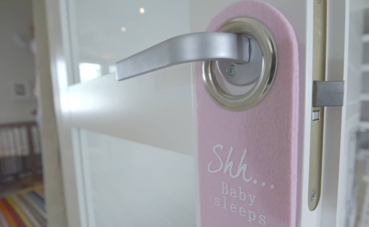 Baby sleeps -lappu huoneen ovessa.