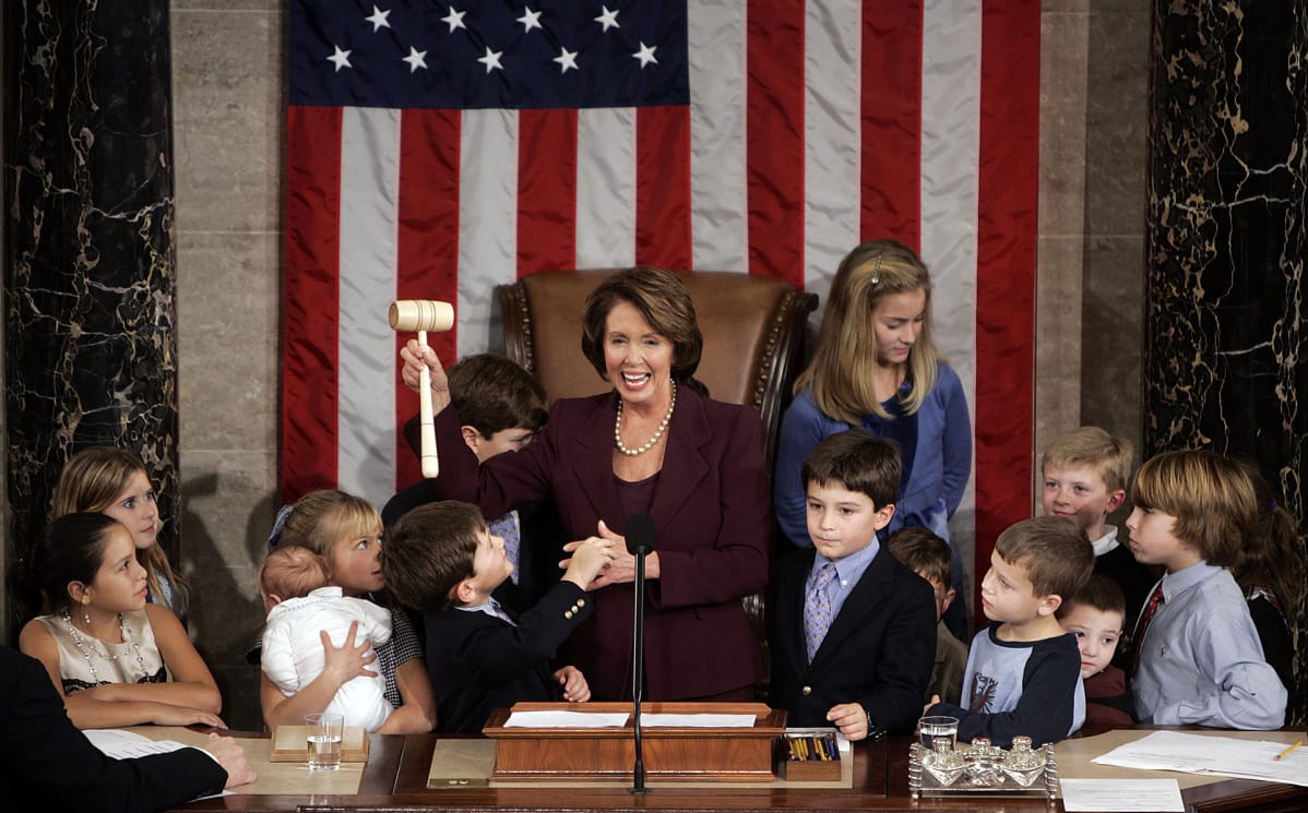 Nancy Pelosi, joukko lapsia ja taustalla Yhdysvaltain lippu.