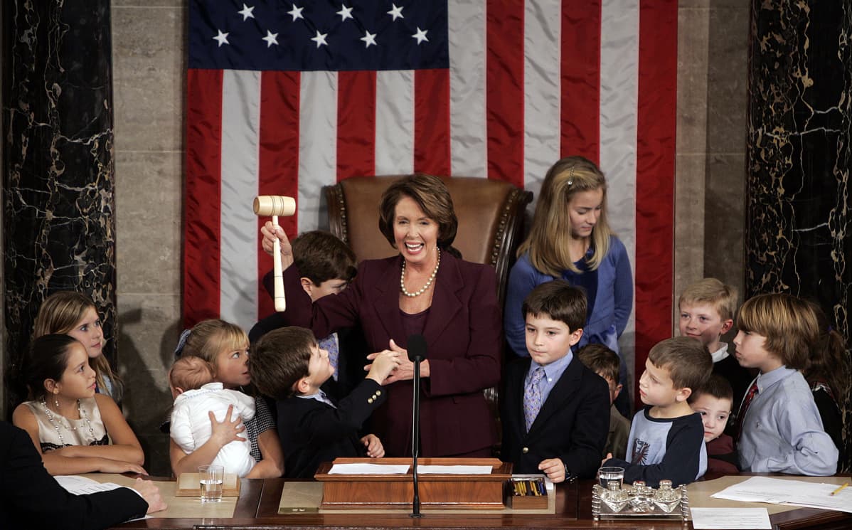 Nancy Pelosi, joukko lapsia ja taustalla Yhdysvaltain lippu.