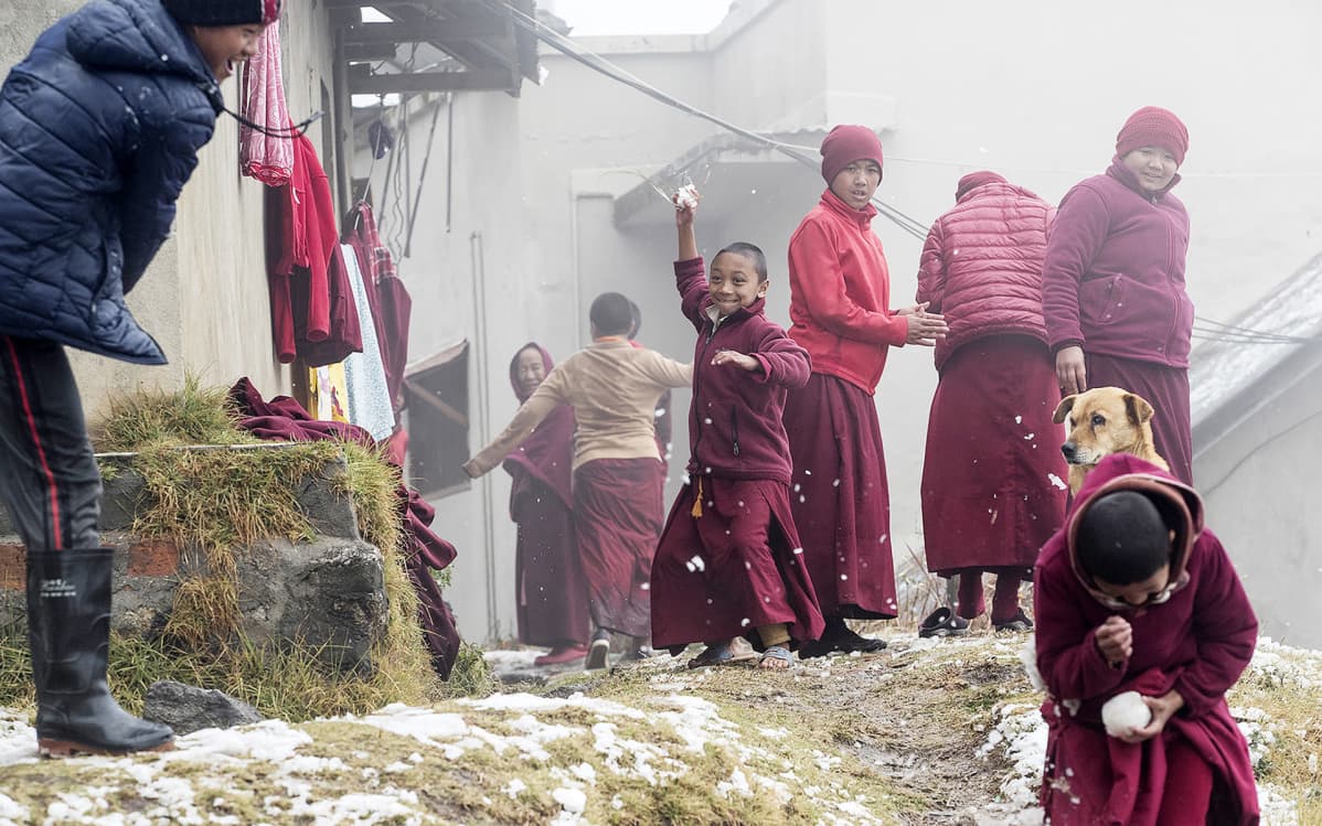 Nuoret buddhalaiset munkit leikkivät lumella viikonloppuna Nagi Gumbassa, Kathmandussa, Nepalissa.