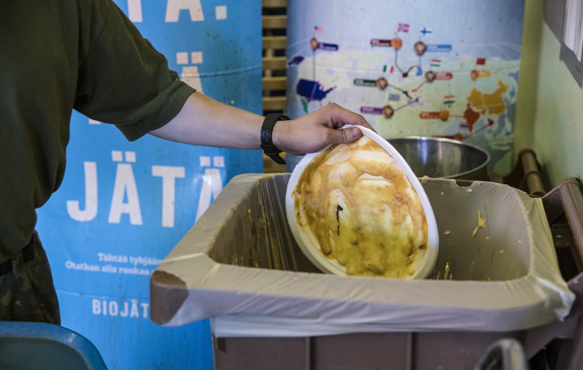Sotilas heittää ruokaa biojätteisiin.