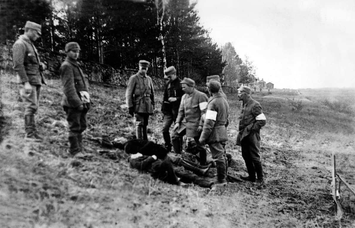 Pohjois-Savon rykmentin suojeluskuntalaiset tarkastelevat teloittamiensa punakaartilaisten ruumiita.