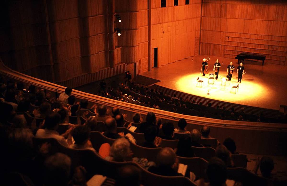 Kamarimusiikkitaiteilijoita ja yleisöä Kuhmo-talon konserttisalissa.