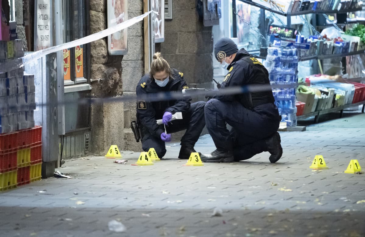 Kaksi poliisia tutkii rikospaikkaa kadulla.
