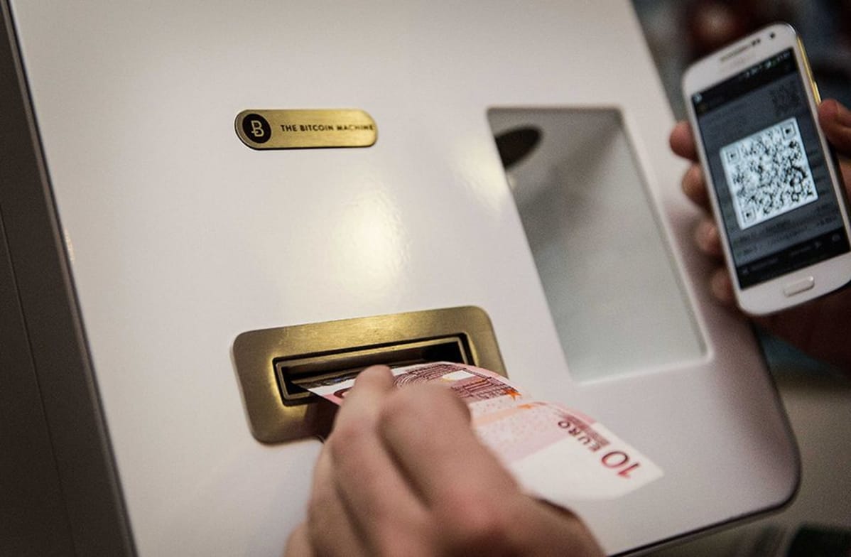 Asiaks vaihtaa käteistä rahaa digirahaksi bitcoinautomaatilla.