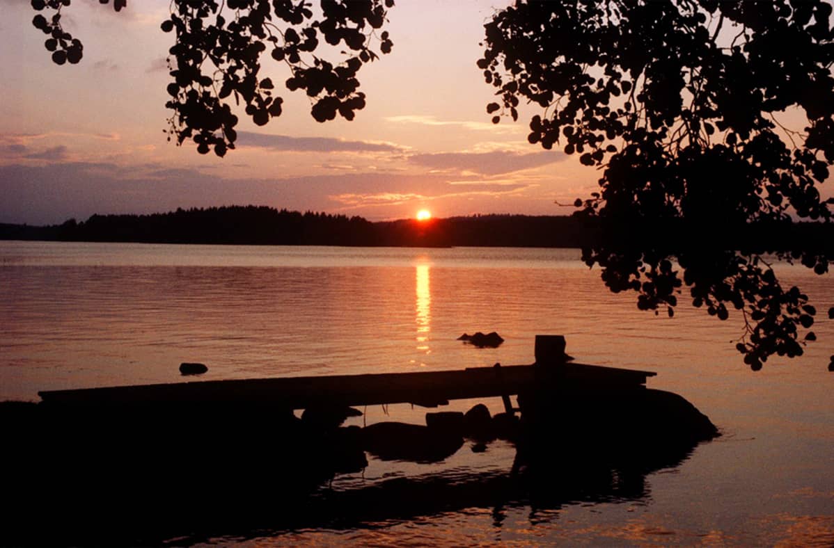 Auringonlasku järven rannalla.