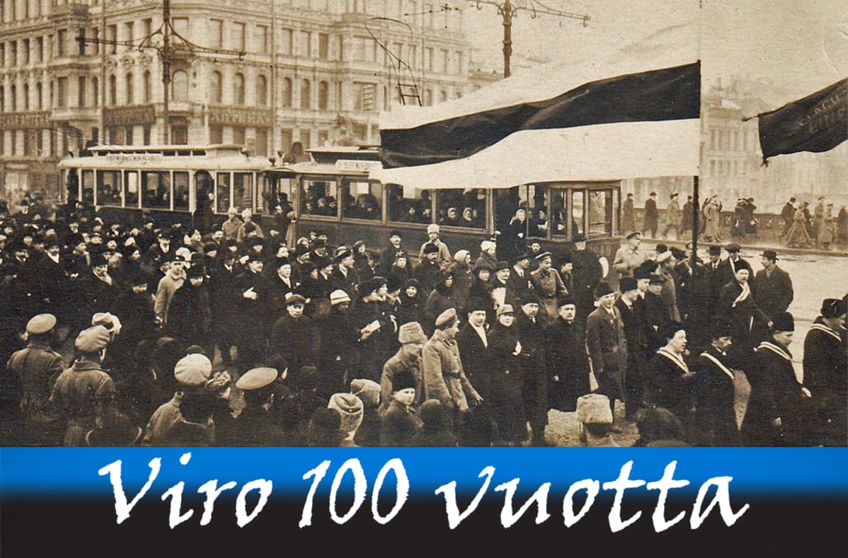 Mustavalkoinen valokuva väkijoukosta, joka marssii kadulla ison Viron lipun jäljessä.