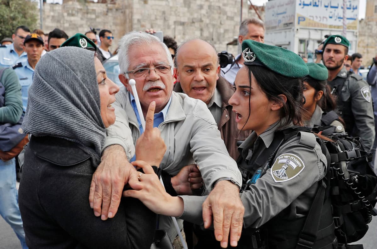 Mies erottamassa palestiinalaisnaista ja Israelin sotilasta