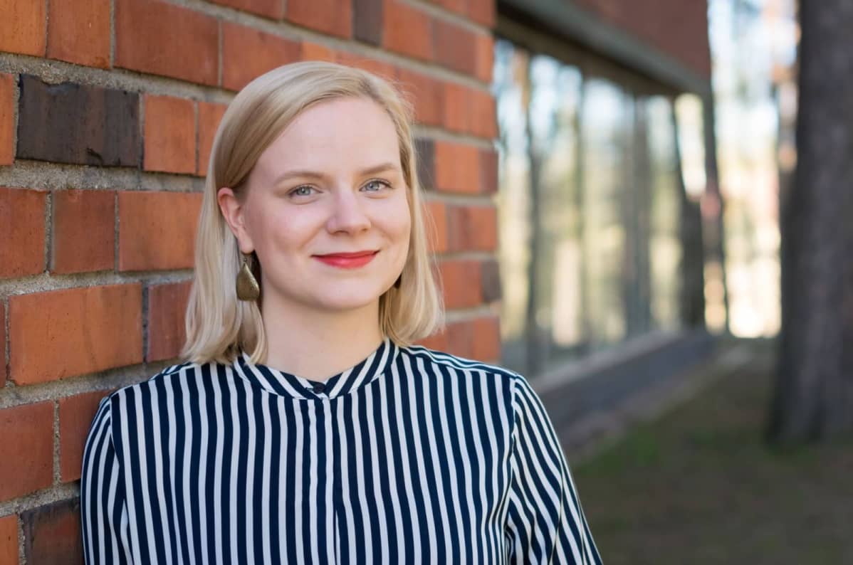 FT Tessa Horilan nojaa punaiseen tiiliseinään