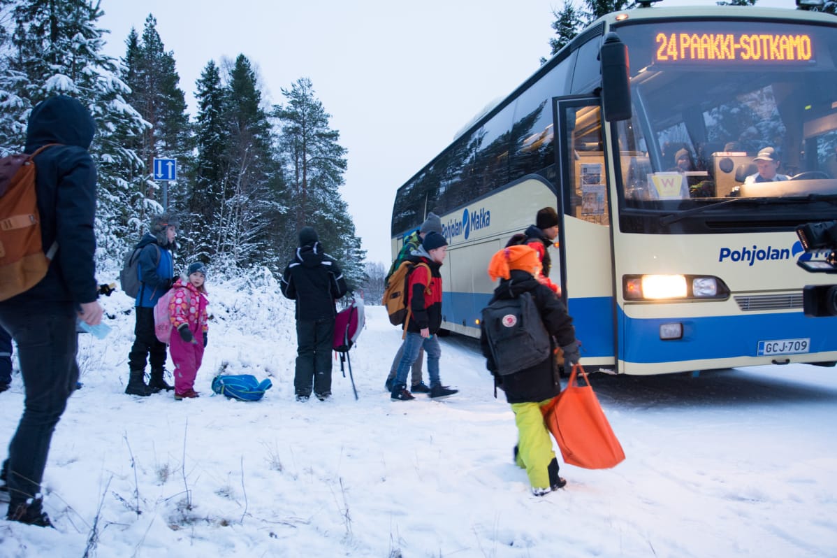 Koululaisia nousemassa linja-auton kyytiin talvella.