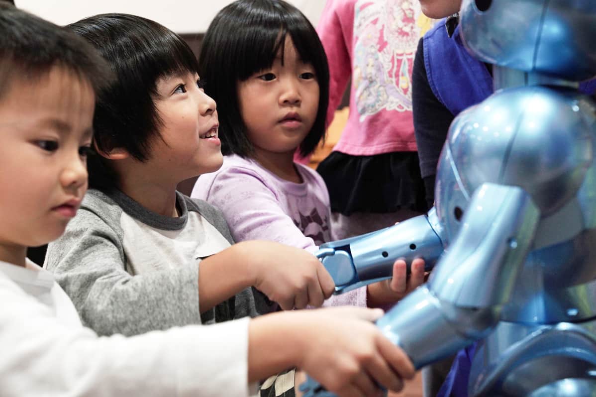 Lapset kättelevät robottia.