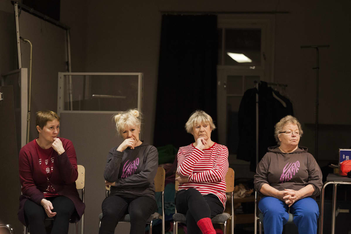 Teatteriharrastajat istuvat rivissä tuoleillaan harjoituksissa.