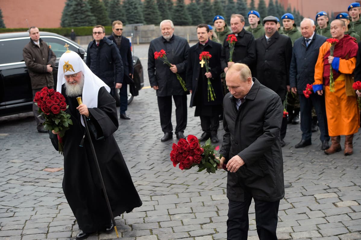 Kuvassa Venäjän ortodoksisen kirkon johtaja patriarkka Kirillja presidentti Vladimir Putin. Molemmilla on käsissään kukkakimput.