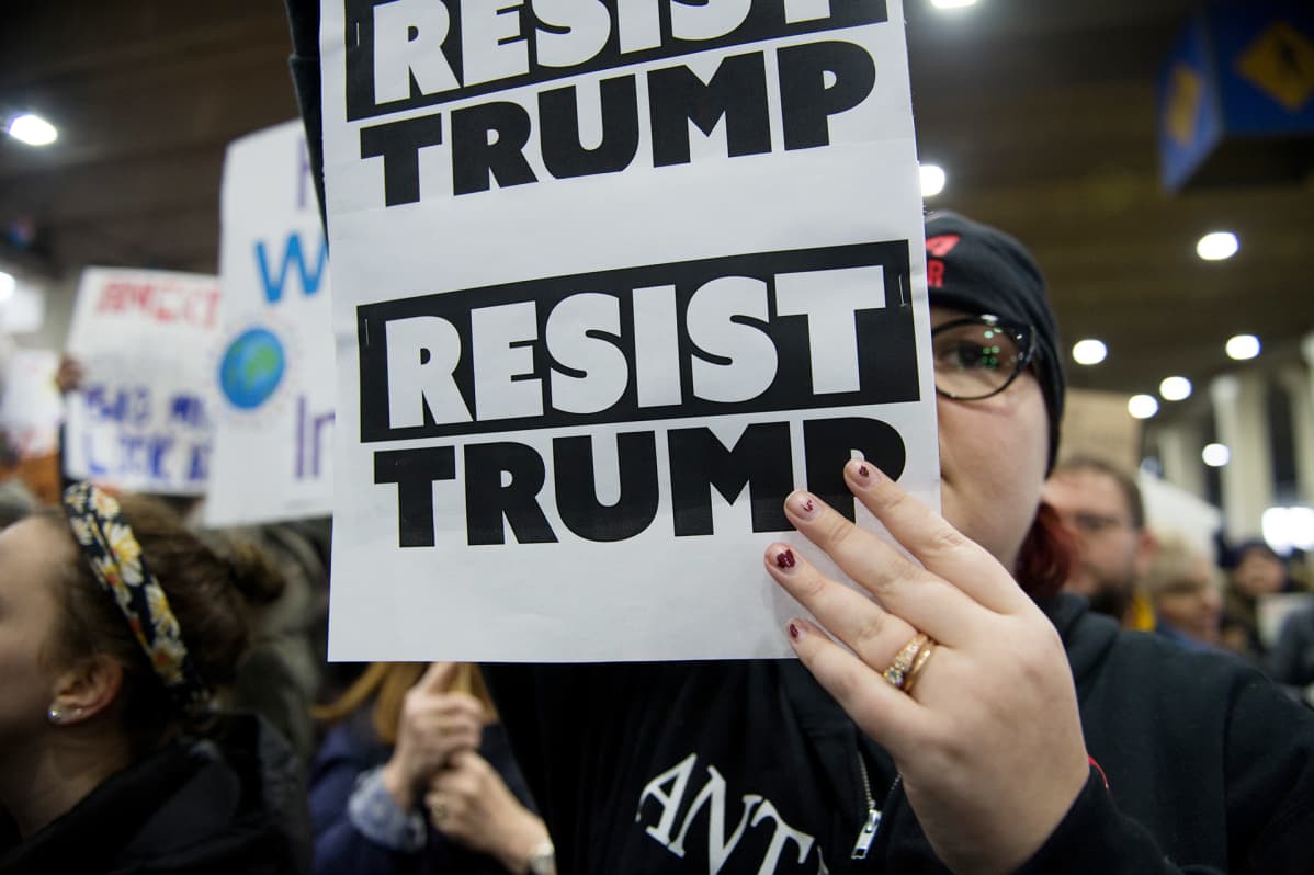 Nainen pitelee resist trump -kylttiä