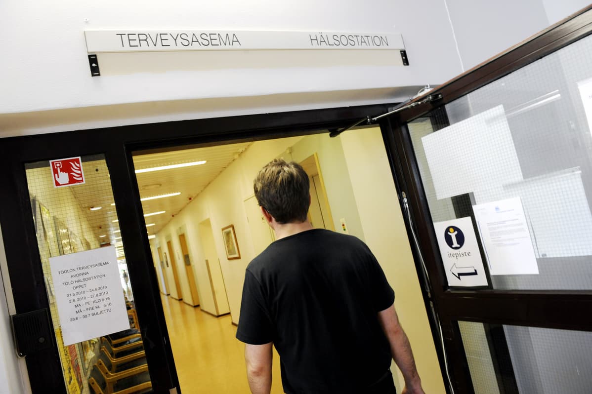 Mies kävelee terveysaseman käytävällä.