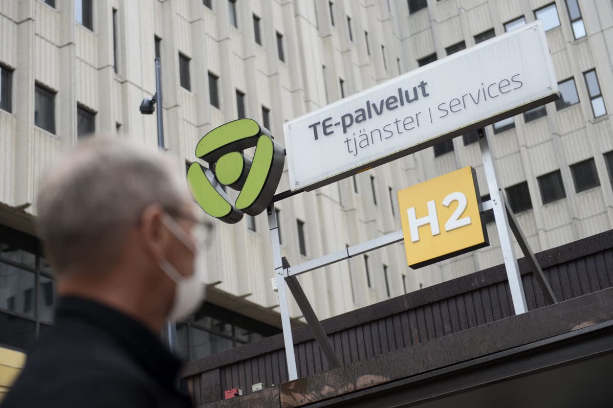 Arbetsförmedlingsbyråns skylt med en man med munskydd i förgrunden