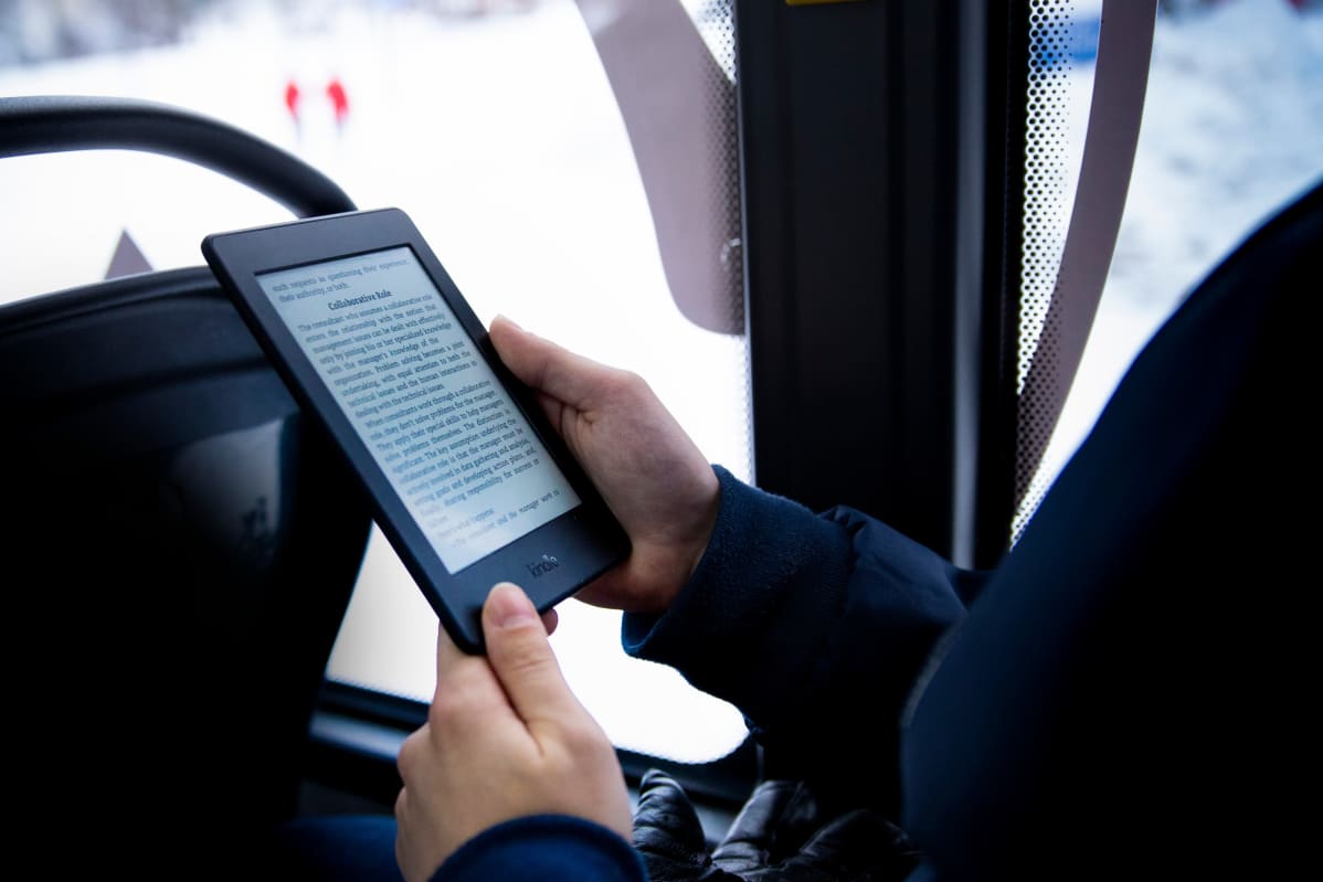 E-kirjan lukulaitteet ovat pieniä ja kevyitä. E-kirjaa luetaan linja-autossa.