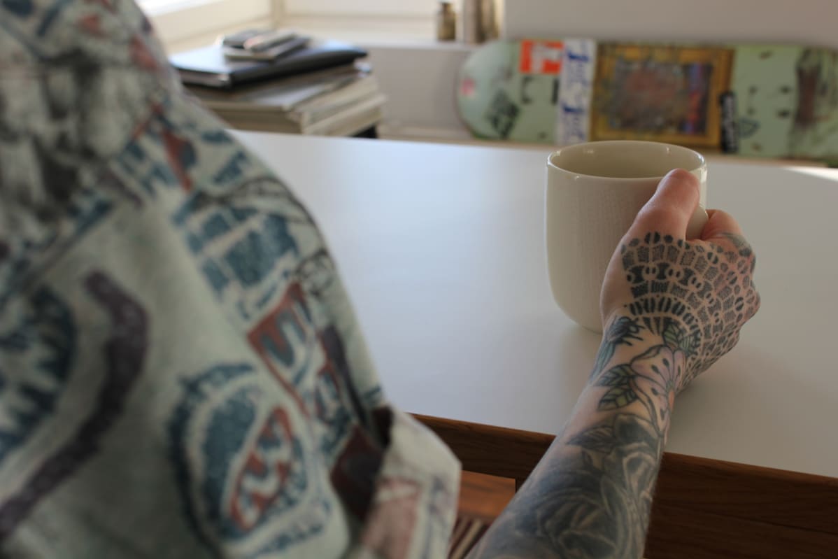 Tatuoitu käsi ja kahvikuppi