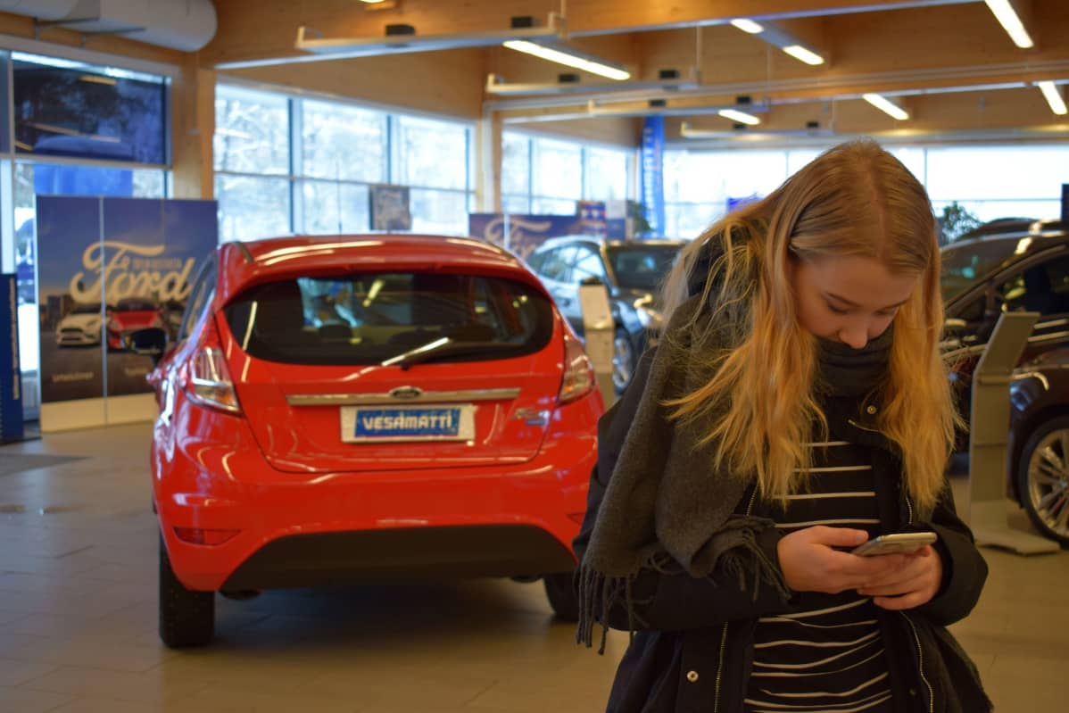 Elisa Grönman viestittelee ystäviensä kanssa autoja katsellessaan.