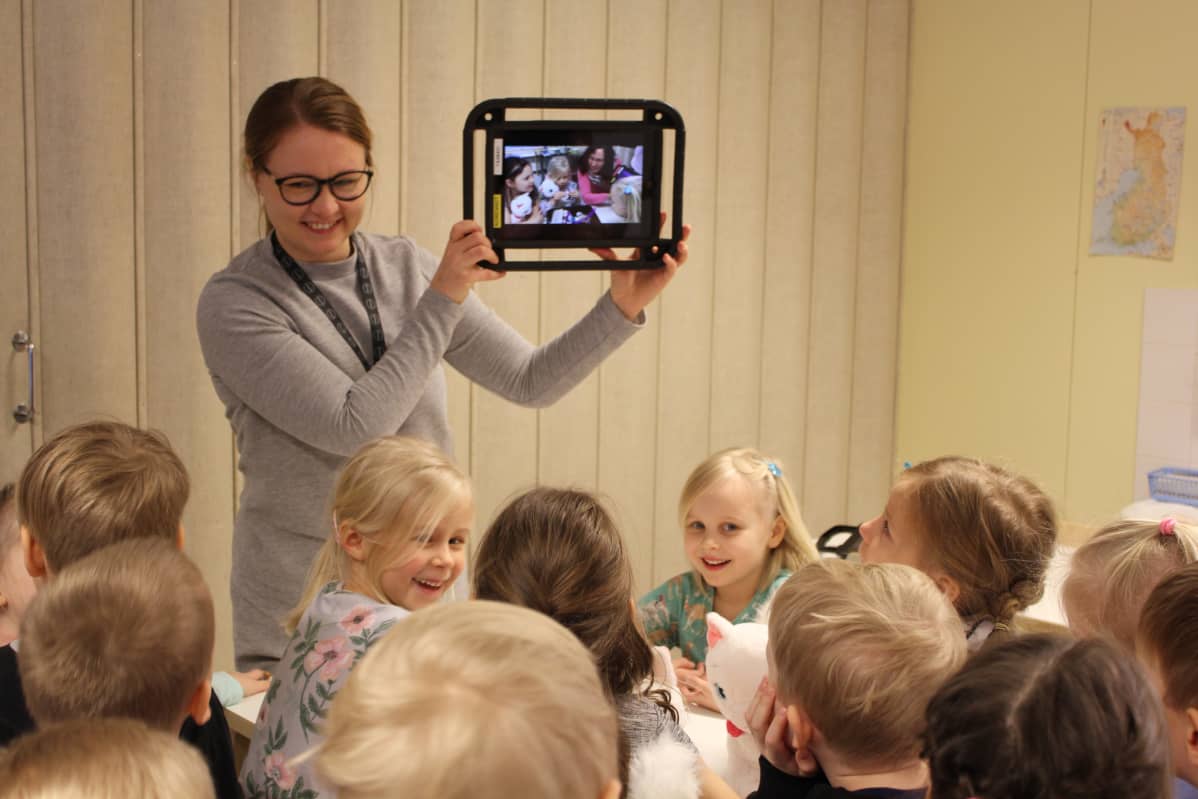 Kotkan varhaiskasvatuksen kehittämiskoordinaattori Tiina Kääpä näyttää lapsille näiden keksimää tarinaa tabletin näytöltä.