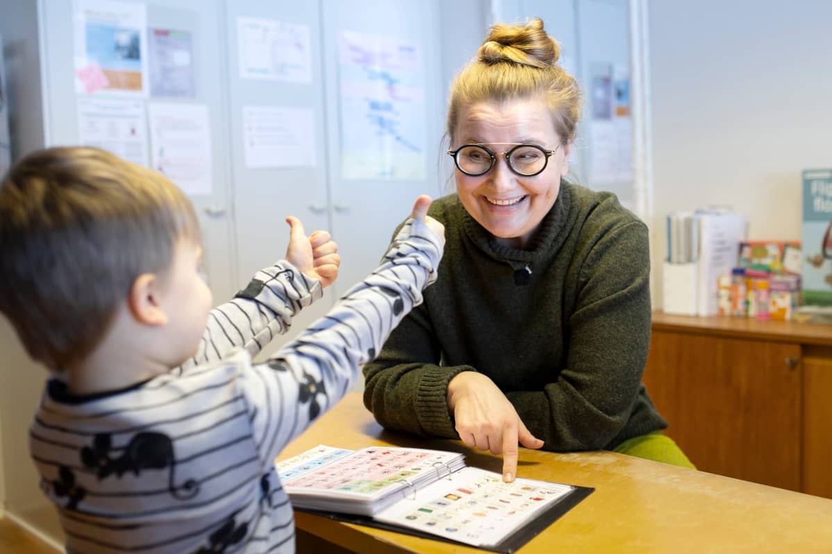 Puheterapeutti Annami Pihlajaniemi puhuu ja viittoo asiakkaalle