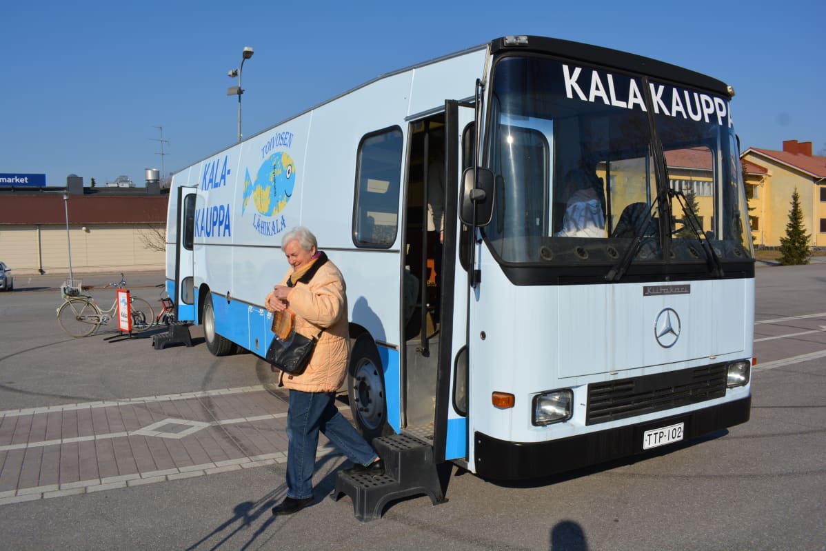Nainen tulee ulos kauppa-autosta.
