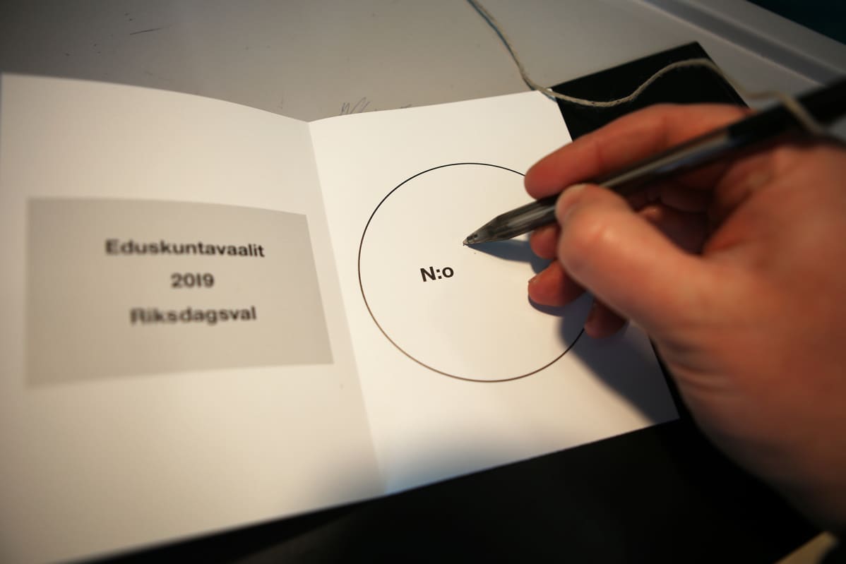 Mies kirjoittaa numeroa äänestyslappuun.