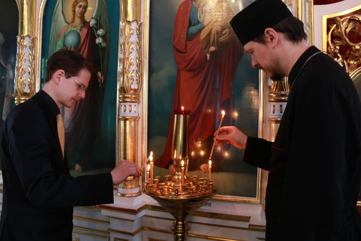Ortodoksikanttori Aleksi Suikkanen ja pastori Aleksander Roszczenko sytyttävät tuohuksia eli kirkkokynttilöitä Pyhän Nikolaoksen kirkossa.