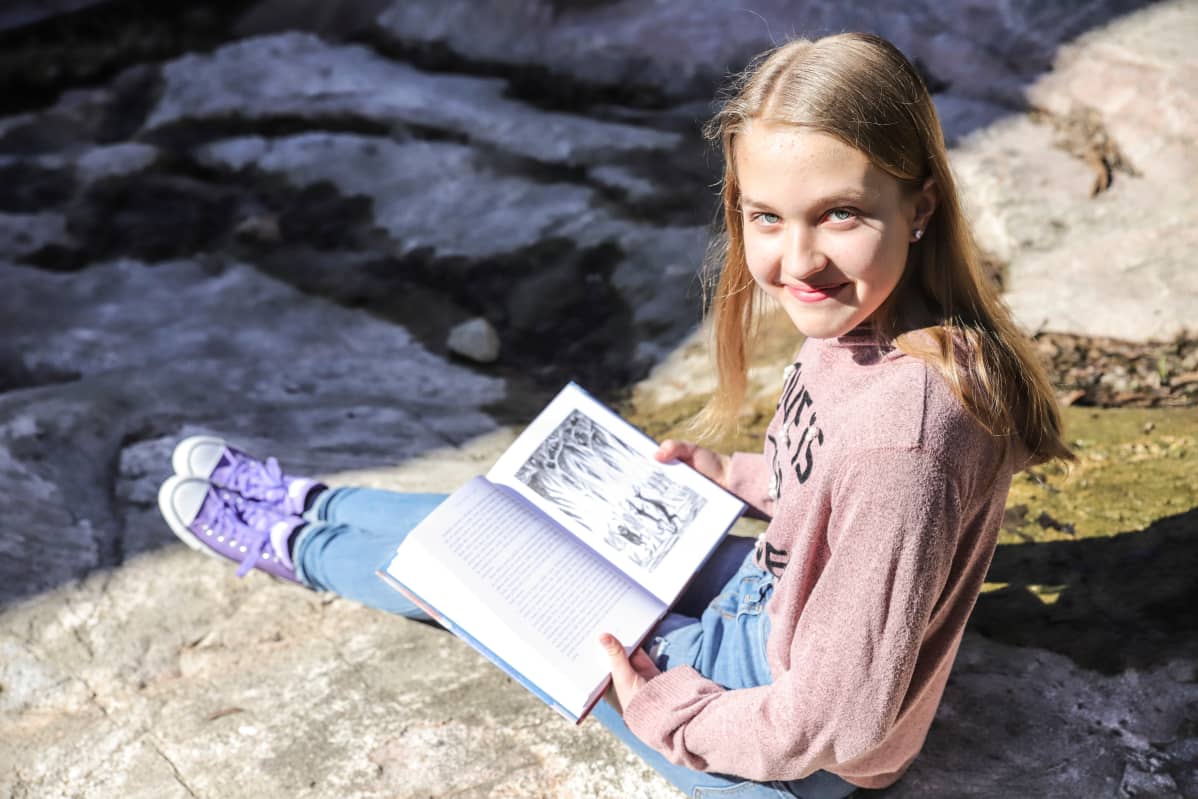 Olivia Lorien Levo istuu ja pitelee Hobitti-kirjaa.