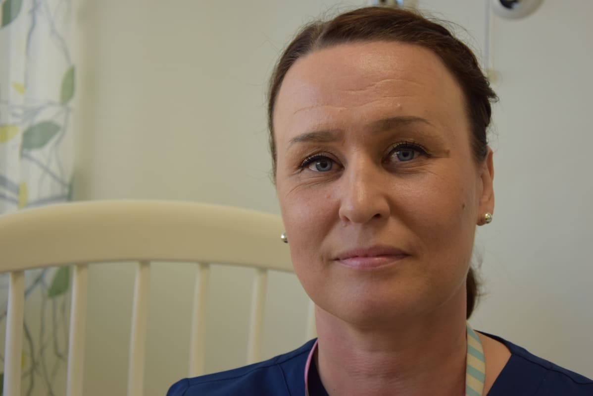 Kätilö istuu keinutuolissa ja katsoo suoraan kameraan