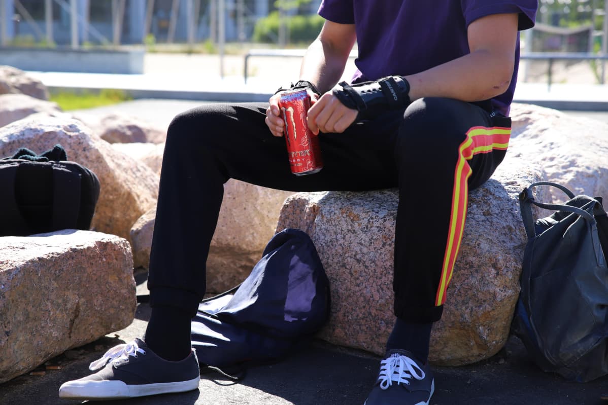 Nuori pitelee kädessään energiajuomaa.