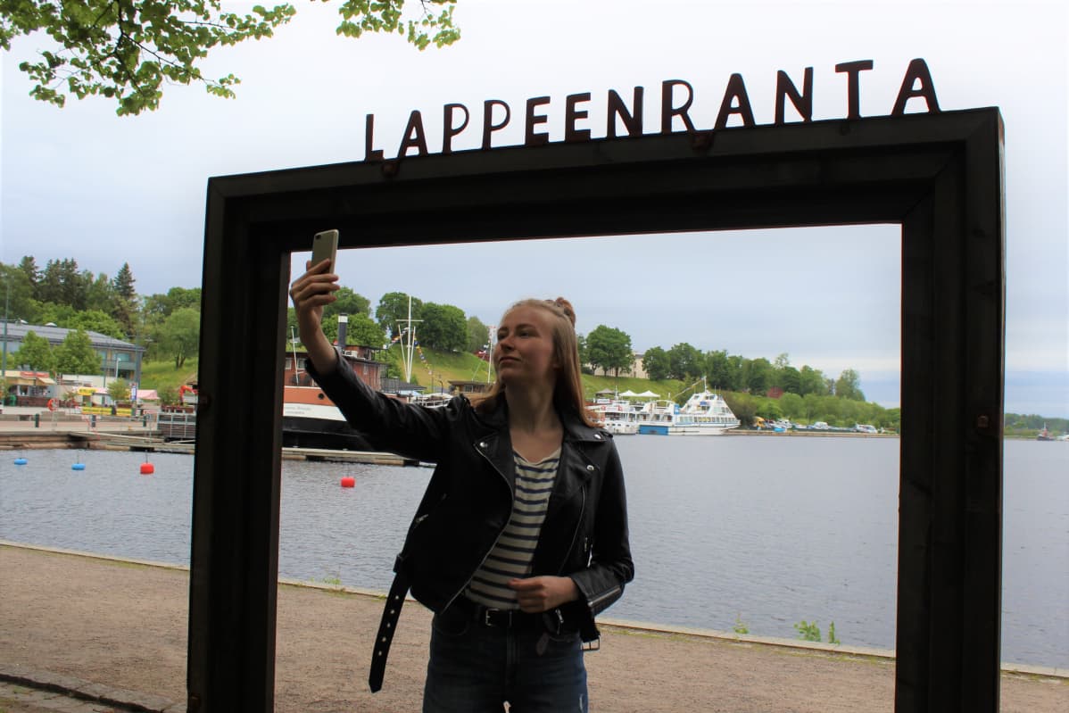 Hanna Muukkonen ottaa itsestään valokuvan Lappeenrannan maisemakehyksissä.