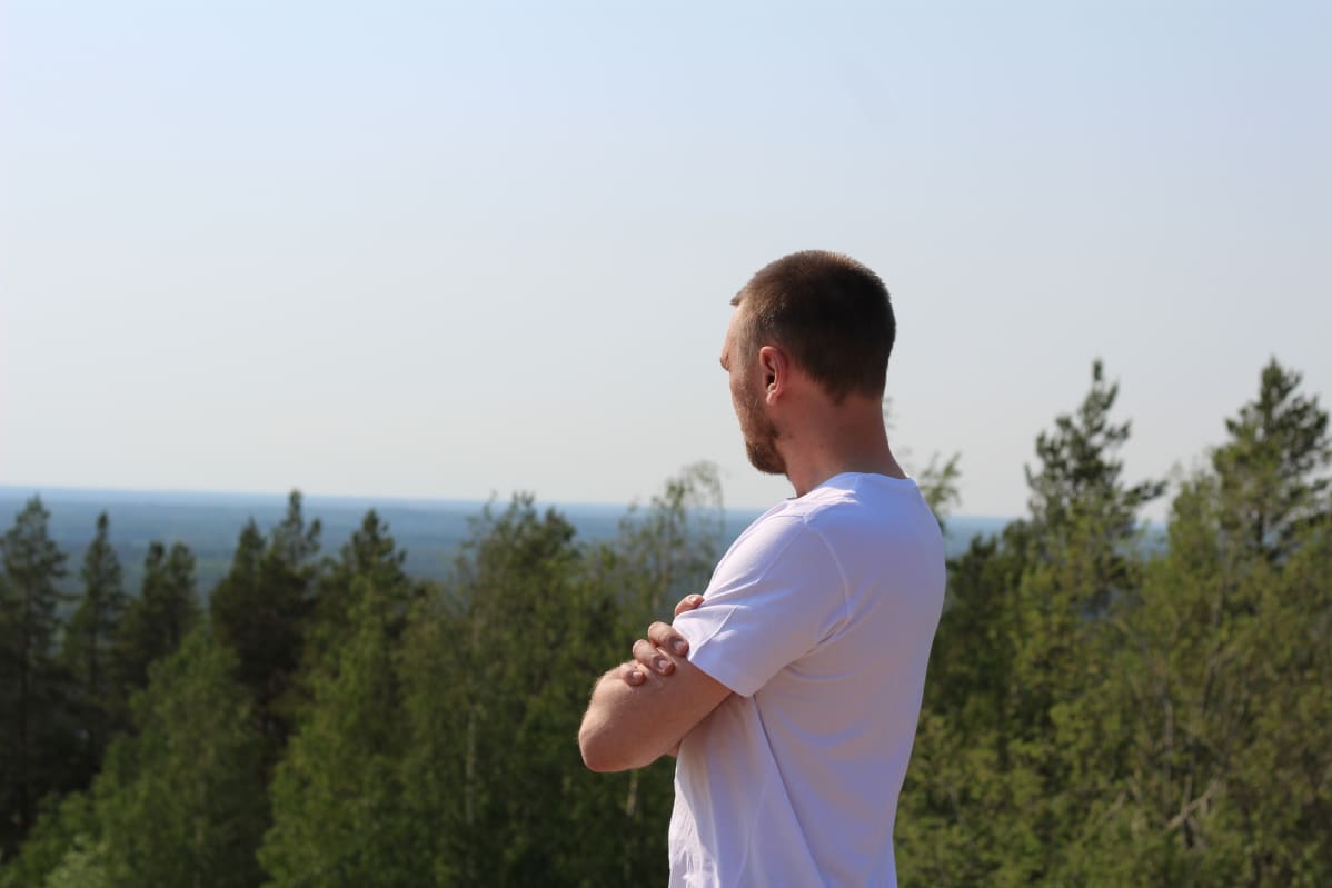 Pauli Finnilä katsoo alla levitäytyvää metsämaisemaa.