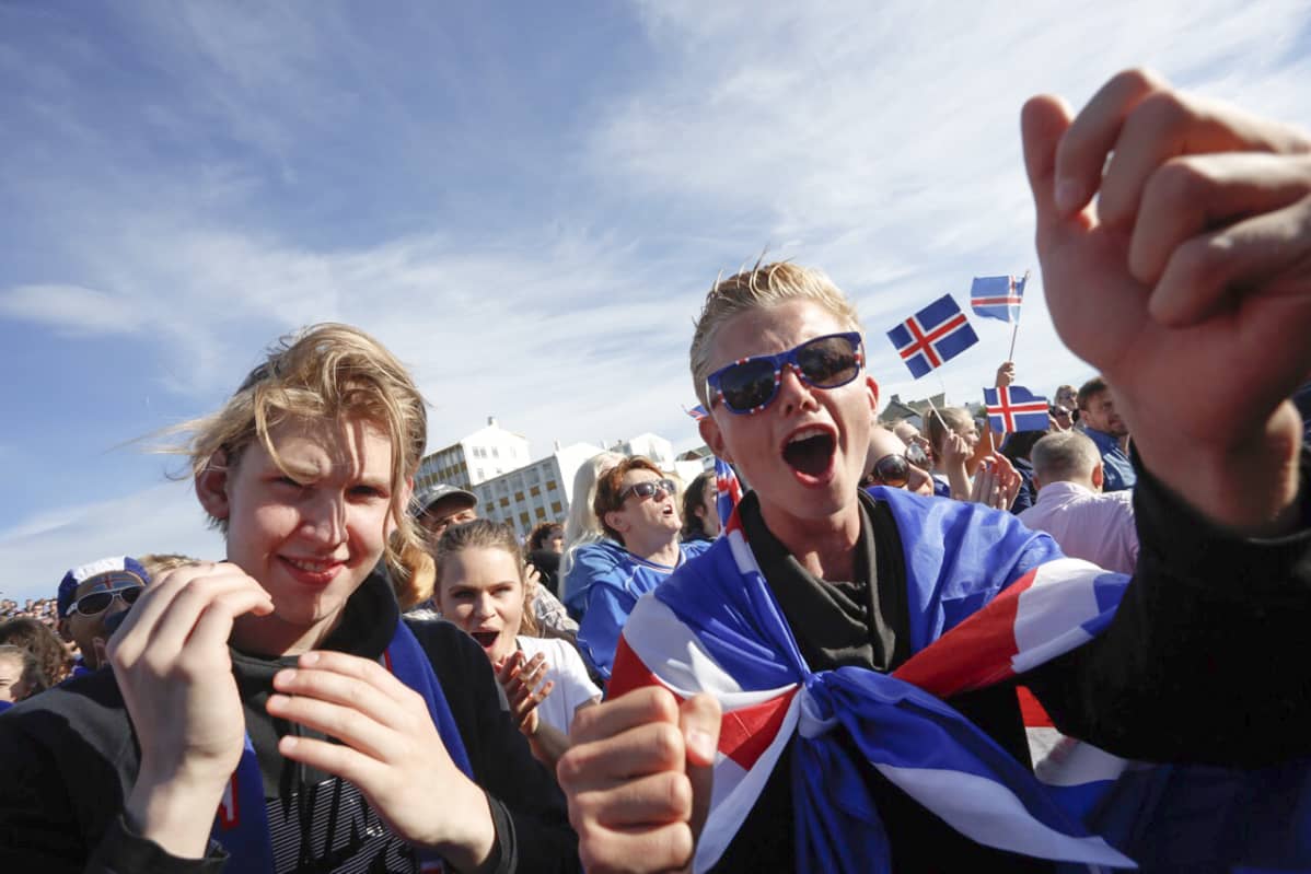 Islantilaisia nuoria ja aikuisia hurraamassa Islannin jalkapallojoukkueelle.