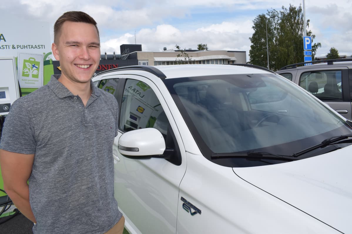 Toni Stenström ladattavan hybridin vieressä.