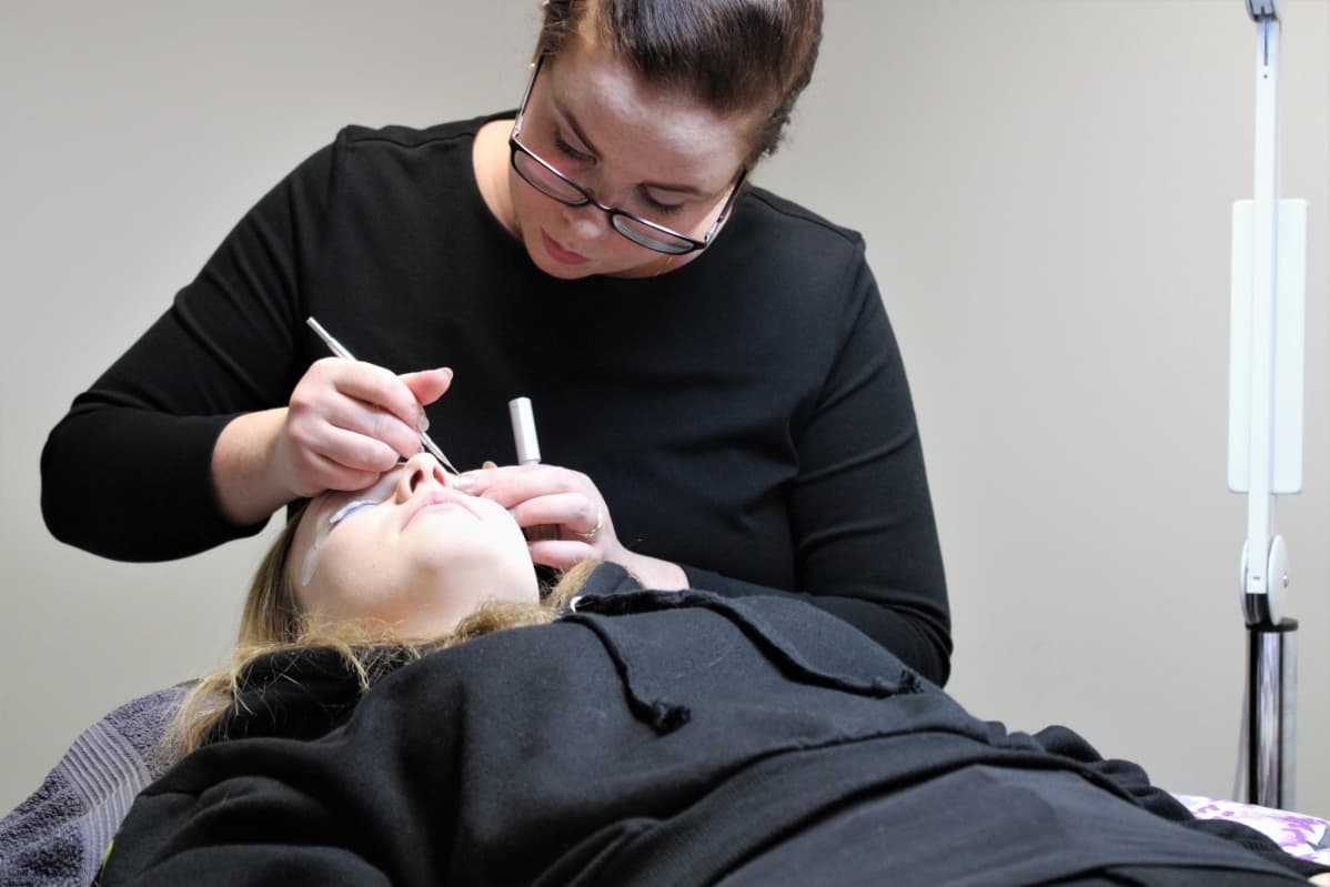 Eevi Pietikäinen tekemässä asiakkaalle ripsien kestotaivutuksia Joensuun Cosmetic Anne -kauneushoitolassa