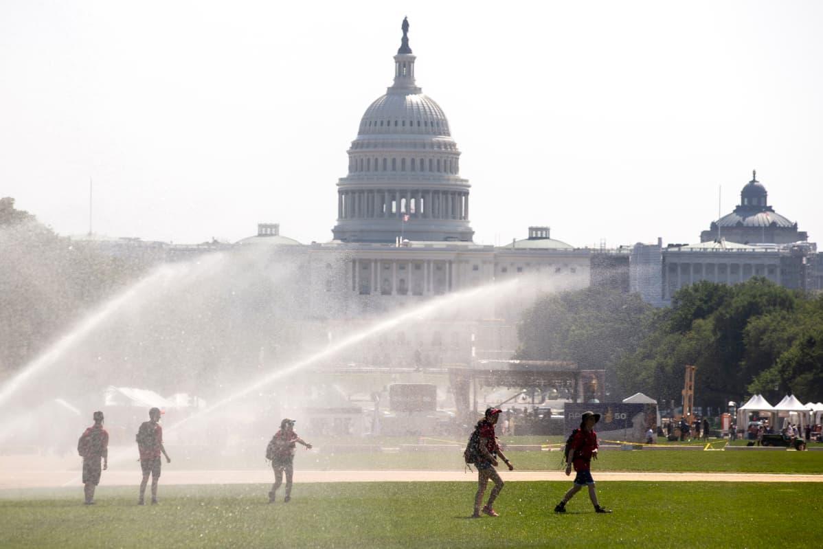 Nuoret kulkivat sprinklerien vesisuihkujen alla Washington DC:ssä 19. heinäkuuta.