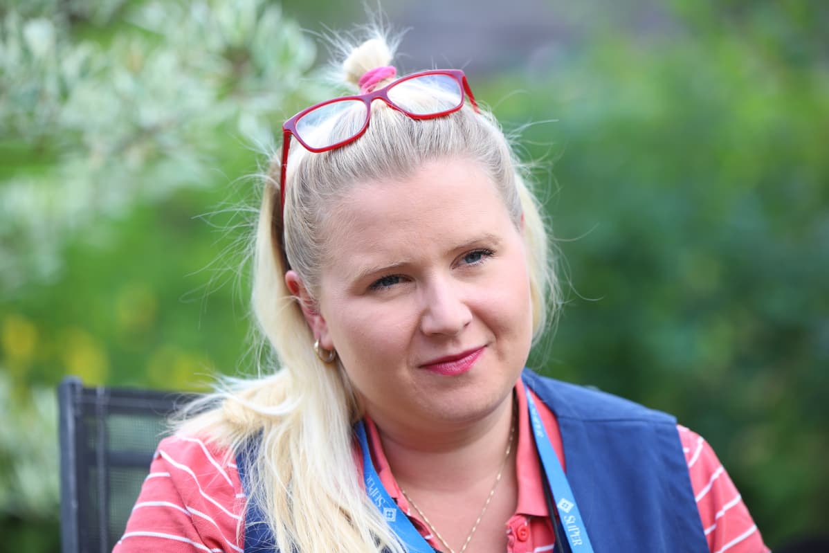 Pitkähiuksinen nainen istuu pihalla