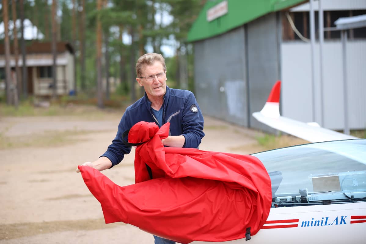 Ilmailuharrastaja Hannu Nurmiranta ottaa purjelentokoneen suojapeiton alta.