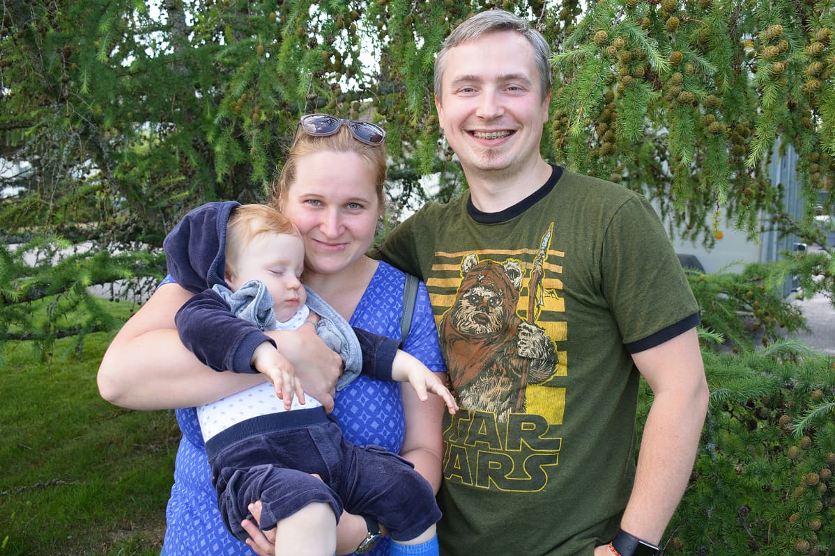 Nainen ja mies seisovat puun edessä vauva sylissään.