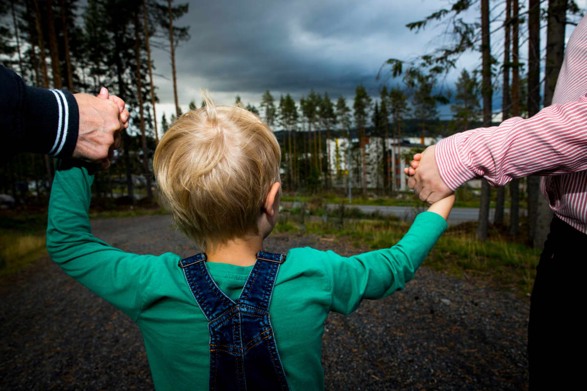 Lapsi pitää vanhempien käsistä kiinni
