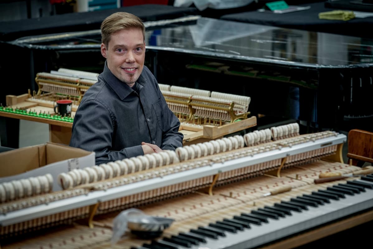 Jami Huovinen F-Musiikin Vantaan myymälässä kunnostettavina olevien flyygeleiden keskellä.