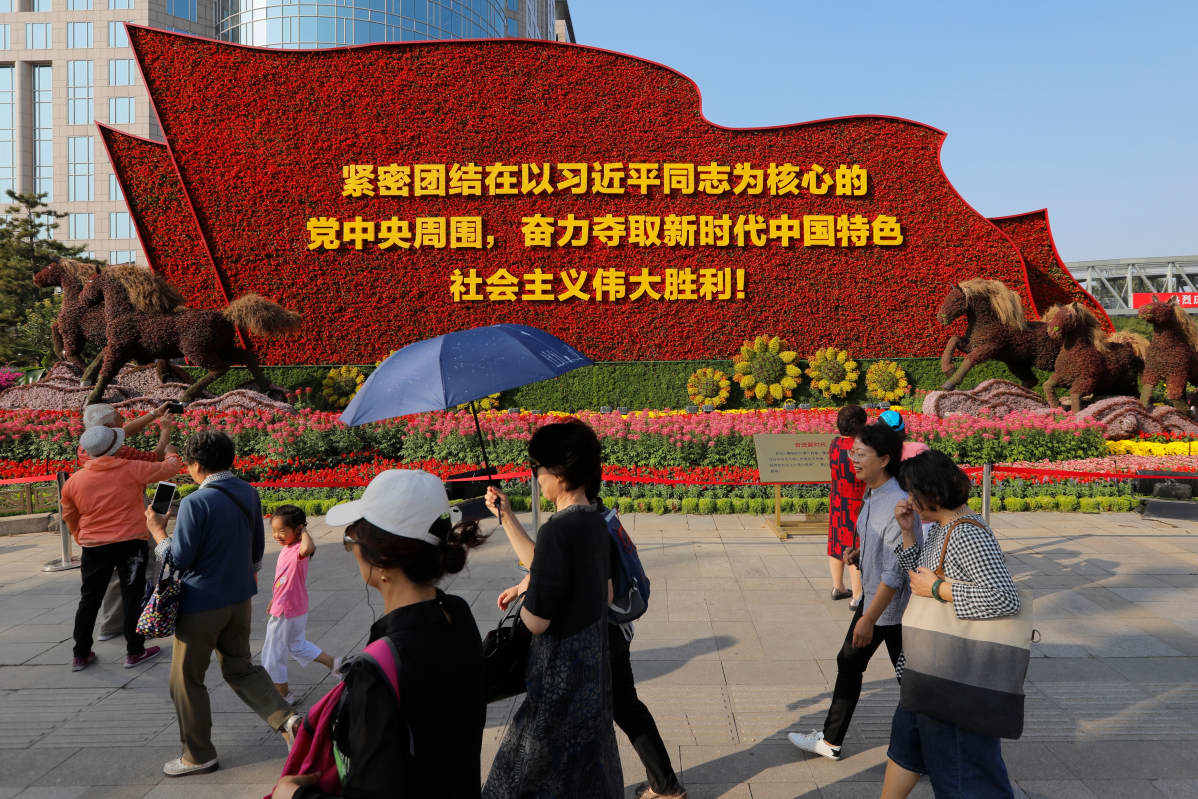 Kukilla koristeltu monumentti julistaa Xi Jinpingin ja kommunismin merkitystä juhlahumun alla Pekingissä.