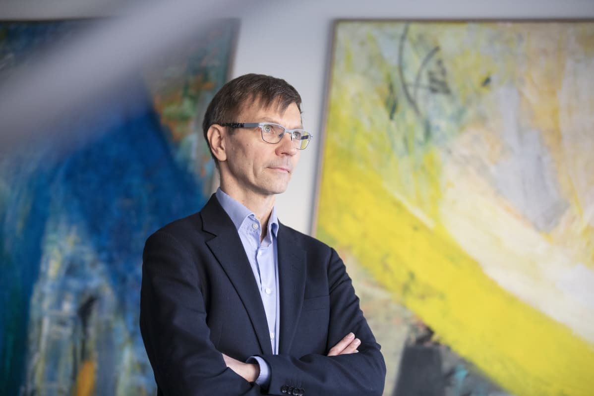 Verohallinnon kehittämisen asiantuntija Jukka Kyhäräinen seisoo kahden suuren maalauksen edessä ja katsoo ikkunan läpi kaukaisuuteen.