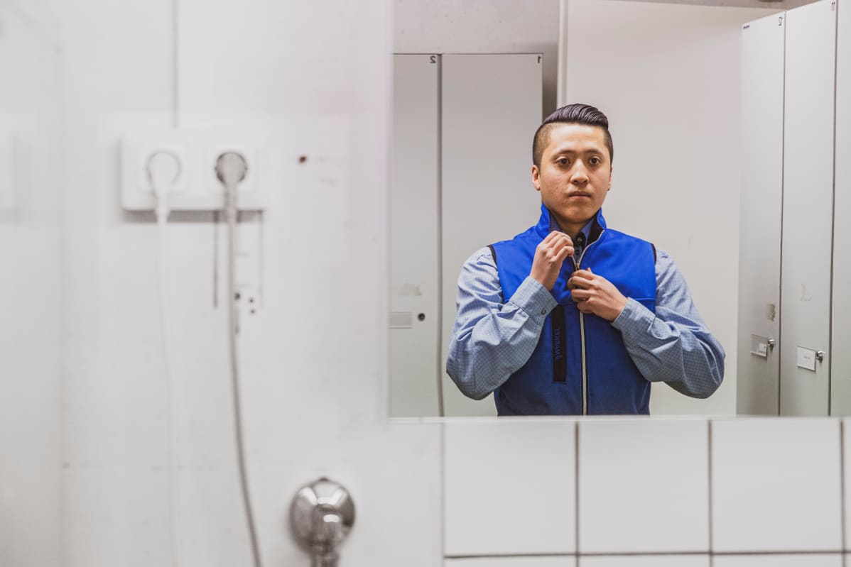 Kini Le pukee myyjän työvaatteita ylleen.