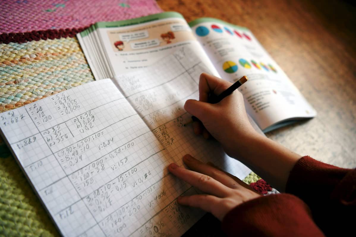 Kuvassa koululainen tekee matematiikan tehtäviä kotonaan.