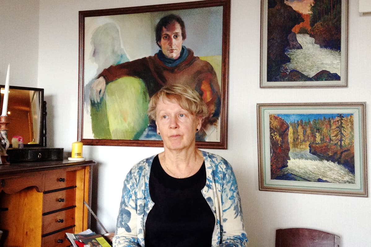 Eve Jaakkola kotonaan, taustalla Hanna Saarikosken maalaus Meksikossa tapetusta Jyri Jaakkolasta.